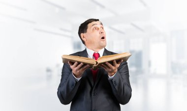 Şaşırmış iş adamı açık bir kitap tutuyor.