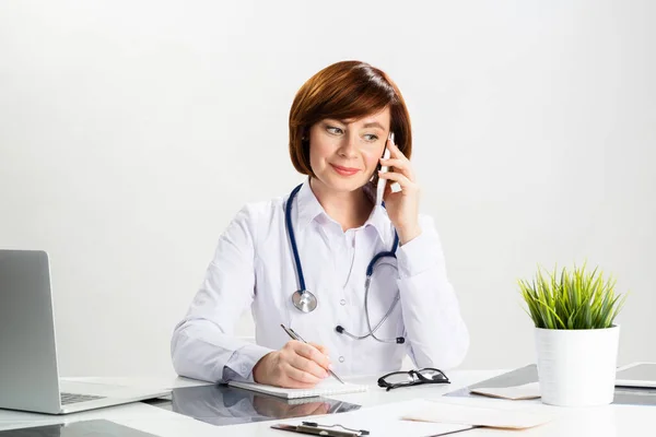 Atractivo médico pelirrojo hablando en smartphone — Foto de Stock