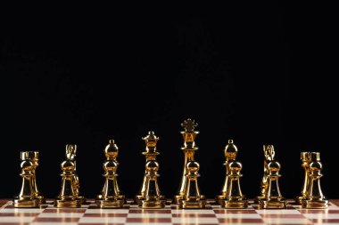 Satranç tahtasında duran altın satranç figürleri