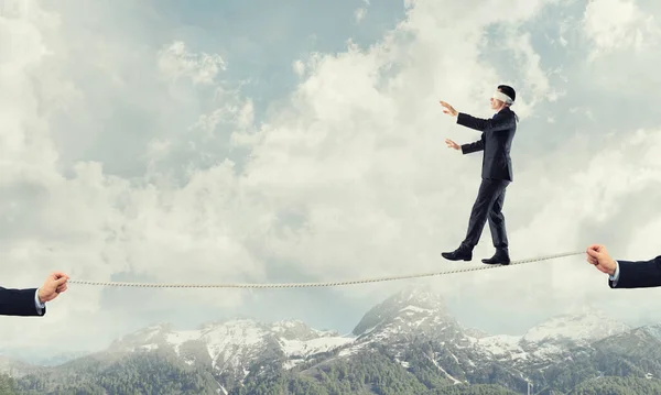 Business concept of risk support and assistance with man balancing on rope — Stock Photo, Image