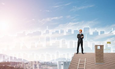 Mühendis adam çatıda dikiliyor ve başka tarafa bakıyor. Karışık ortam