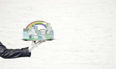 Elle tutulan metal tepsi ahşap arka planda modern şehir modeli.