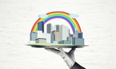 Elle tutulan metal tepsi ahşap arka planda modern şehir modeli.