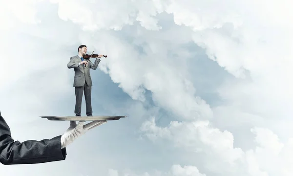 Uomo d'affari su vassoio di metallo suonare il violino sullo sfondo cielo blu — Foto Stock