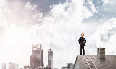 Mühendis adam çatıda dikiliyor ve başka tarafa bakıyor. Karışık ortam