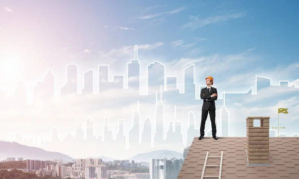 Inženýr stojí na střeše a dívá se jinam. Smíšená média — Stock fotografie
