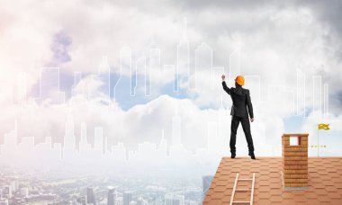 Erkek mimar mavi gökyüzüne modern şehrin siluetini çizer. Karışık ortam