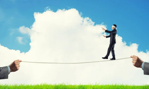 Business concept of risk support and assistance with man balancing on rope — Stock Photo, Image