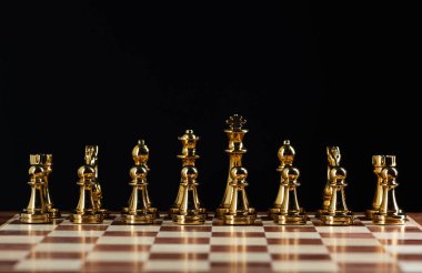 Satranç tahtasında duran altın satranç figürleri