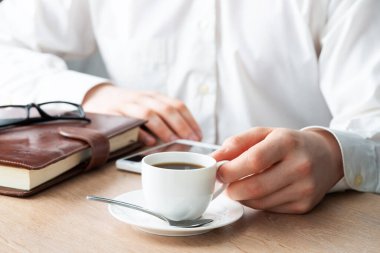 Beyaz gömlekli adam akıllı telefon kullanıyor.