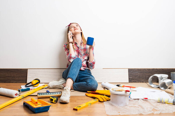 Dreamy girl talking on smartphone on floor