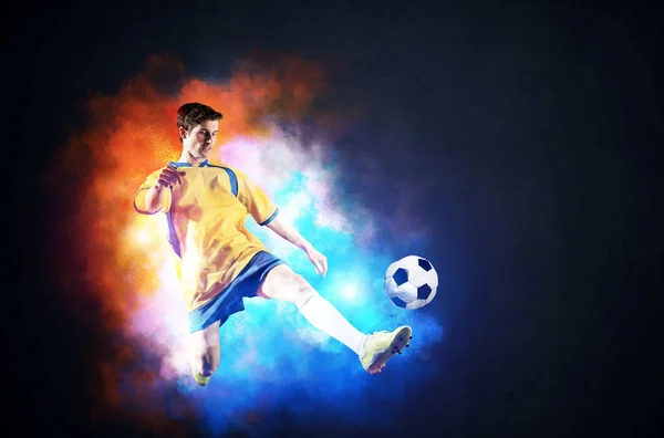 Футболіст штовхає м'яч в барвистий дим — стокове фото