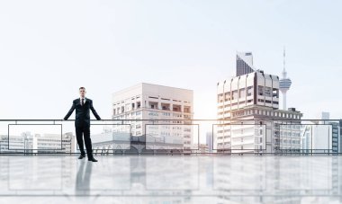 Gökdelenlerin üzerinde gün doğumu ve yeni bir güne bakan iş adamı