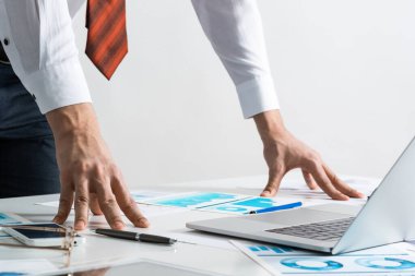 Takım elbiseli ve kravatlı bir iş adamı masanın yanında duruyor.