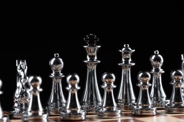 Satranç tahtasının üzerinde duran gümüş satranç figürleri