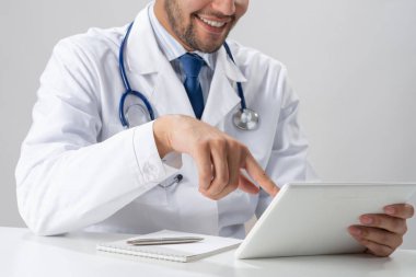 Tablet bilgisayar kullanan mutlu genç bir doktor.