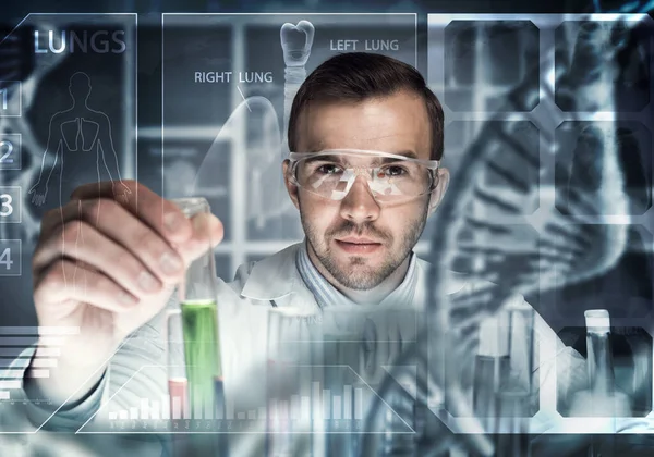 Νεαρός επιστήμονας που αναμιγνύει αντιδραστήρια σε γυάλινη φιάλη σε κλινικό εργαστήριο — Φωτογραφία Αρχείου