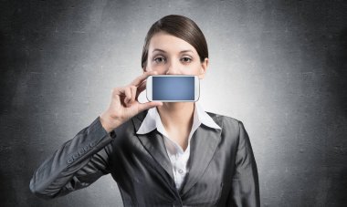 Ağzını akıllı telefonla kapatan kadın.
