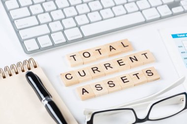 Küpler üzerindeki harflerle birlikte toplam varlık kavramı. Malzemelerle dolu ofis hayatı. Düz gri yüzey, bilgisayar klavyesi ve not defteriyle yatıyordu. Sermaye yatırımı ve finansal analizler.