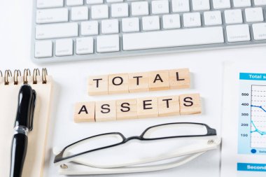 Küpler üzerindeki harflerle birlikte toplam varlık kavramı. Malzemelerle dolu ofis hayatı. Düz gri yüzey, bilgisayar klavyesi ve not defteriyle yatıyordu. Sermaye yatırımı ve finansal analizler.