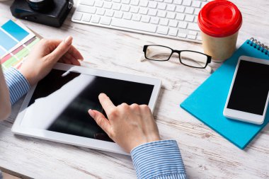 Masada oturup tablet bilgisayar kullanan bir iş danışmanı. Dijital teknoloji ve akıllı cihazlar. Ahşap masada müdürün olduğu şirket işyeri. İş mesleği ve yenilik.