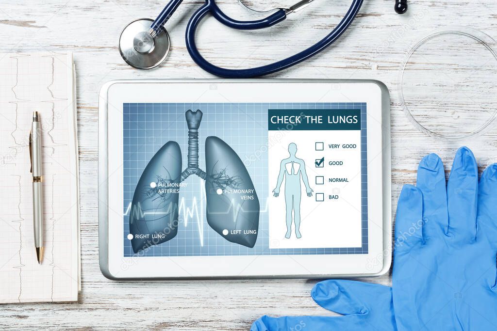 Medical diagnostics in modern pulmonology. Tablet computer with medical application interface on screen. Top view stethoscope and cardiogram on wooden desk. Digital tuberculosis screening test