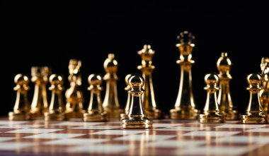 Satranç tahtasında duran altın satranç figürleri. Entelektüel ve taktik bir oyun. Strateji planlaması, liderlik ve takım çalışması konsepti. Siyah arkaplanda yakın plan altın satranç taşları.