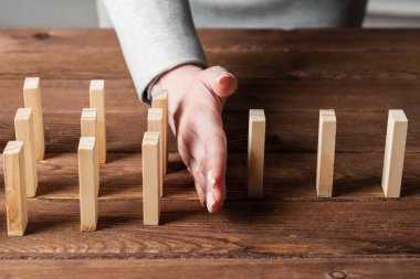 Dominoları tahta masaya düşmekten koruyan iş kadını. Kriz anında iş yardımı ve liderlik. Operatif iş çözümü ve durumun istikrar kazanması. Profesyonel risk yönetimi