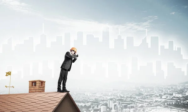 Ingegnere uomo in piedi sul tetto e guardando in binocolo. Misto m — Foto Stock