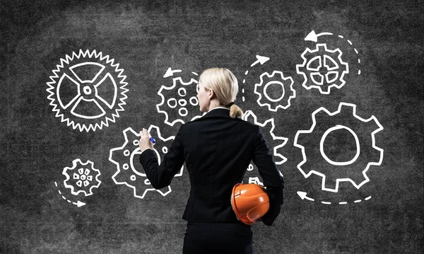 Businesswoman draws gears mechanism on blackboard — Stock Photo, Image