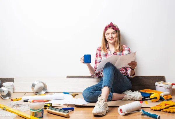 Lachend meisje zittend op de vloer met blauwdruk — Stockfoto