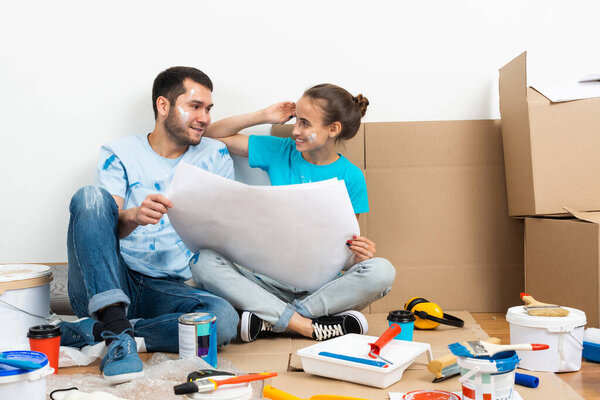 Happy couple sitting on floor with blueprint.