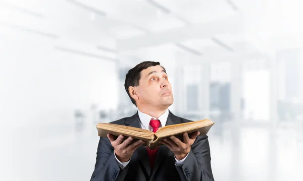 Hombre de negocios serio con libro abierto mirando hacia arriba — Foto de Stock