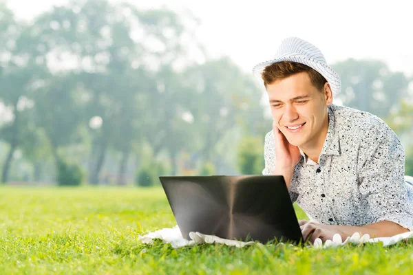 Jeune homme travaillant dans le parc avec un ordinateur portable — Photo