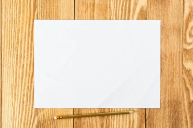 Tahta masanın üzerinde duran bir kağıt parçası.