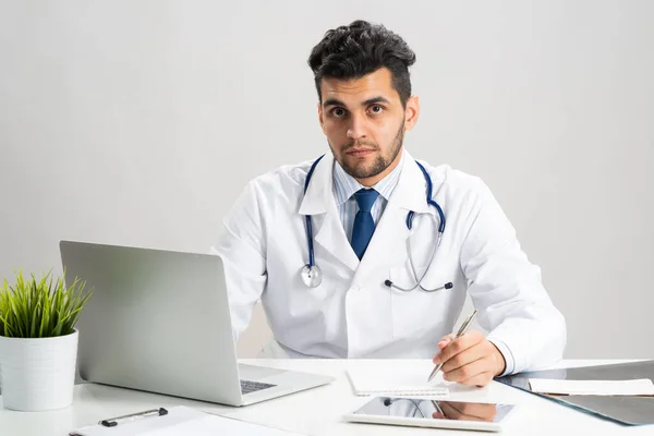 Schöner Doktor sitzt am Schreibtisch im Büro — Stockfoto