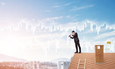 Çatıda takım elbiseli genç bir işadamı var. Karışık ortam