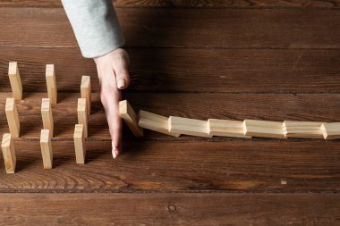 Dominoları tahta masaya düşmekten koruyan iş kadını. Kriz anında iş yardımı ve liderlik. Operatif iş çözümü ve durumun istikrar kazanması. Profesyonel risk yönetimi