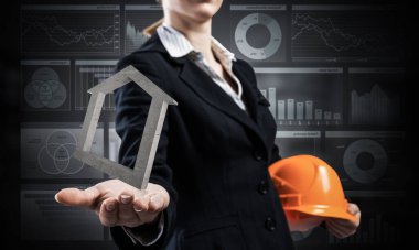 Emlakçı Palm 3D ev sembolü taşıyor. Güvenlik kasklı takım elbiseli bir kadın. Mühendislik ve proje yönetimi. Emlak yatırımı ve konut kredisi finansal konsepti.