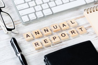 Küpler üzerine harf içeren yıllık rapor kavramı. Malzemelerle dolu ofis hayatı. Bilgisayar klavyesi ve deri cüzdanı olan düz, eski, tahta bir masa. Şirket geliştirme ve analiz