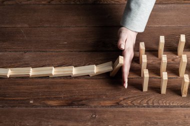 Dominoları tahta masaya düşmekten koruyan iş kadını. Kriz anında iş yardımı ve liderlik. Operatif iş çözümü ve durumun istikrar kazanması. Profesyonel risk yönetimi