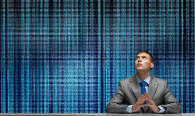 Elleri bağlı adam yukarı bakıyor. Masada oturan genç bir iş adamı. Programcı arka planda dijital çizgilerle takım elbise ve kravat takıyor. Gelecekteki yenilik teknolojisi