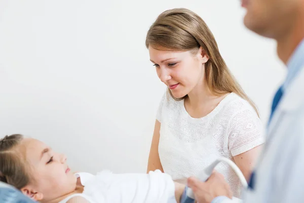 医生在医院检查小病人的腹部 在小女孩肚子上移动传感器的声谱师 近距离超声波扫描仪在男性手中 在诊所检查孩子的母亲 — 图库照片