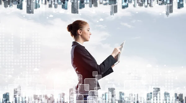 Young businesswoman with tablet computer on modern cityscape background. Double exposure concept with beautiful woman in business suit. Digital technology in stock trading and real estate investment