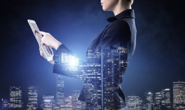 Tablet bilgisayar kullanan bir iş kadını. Gece kenti ve takım elbiseli kadınla çift pozlama konsepti. Gayrimenkul yatırımı ve geliştirme. Strateji planlaması ve yönetiminde dijital teknoloji.