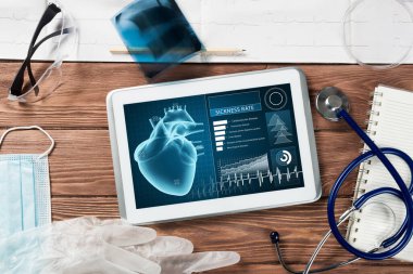 Beyaz tablet bilgisayar ve doktor aletleri ahşap masada.