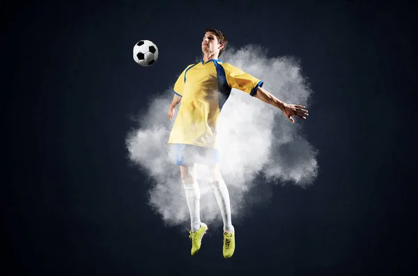 Soccer player jumping with ball in smoke — Stock Photo, Image