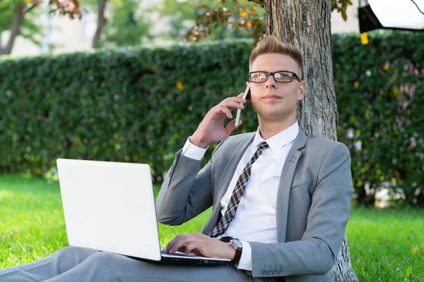 businessman speaks on the phone in the park. work out of the office