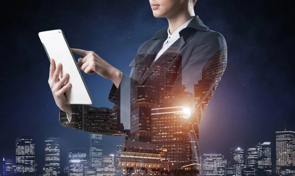 Tablet bilgisayar kullanan bir iş kadını. Gece kenti ve takım elbiseli kadınla çift pozlama konsepti. Gayrimenkul yatırımı ve geliştirme. Strateji planlaması ve yönetiminde dijital teknoloji.