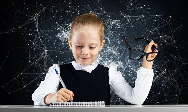 Leende liten flicka i skolkläder gör läxor — Stockfoto